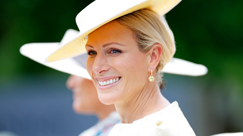 Zara Tindall smiles and wears a yellow outfit with a matching yellow hat