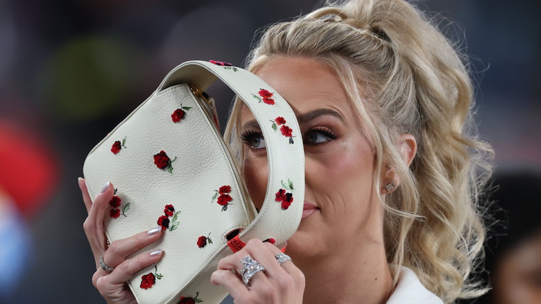 Brittany Mahomes holding a purse in front of her face