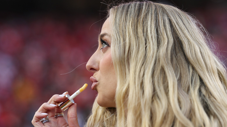 Brittany Mahomes putting on lip gloss while making a silly face