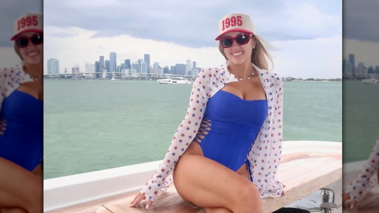 Brittany Mahomes on a boat in a swimsuit in front of a city skyline.