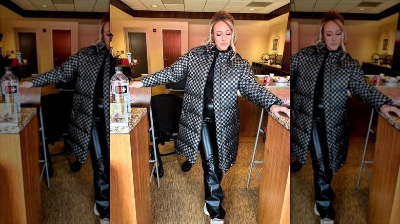 Mahomes in a small room, posing in dark winter clothing, looking at the floor.