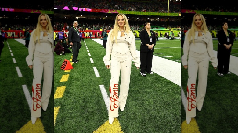 Brittany Mahomes poses on the sideline of the LIX superbowl in an all white outfit.