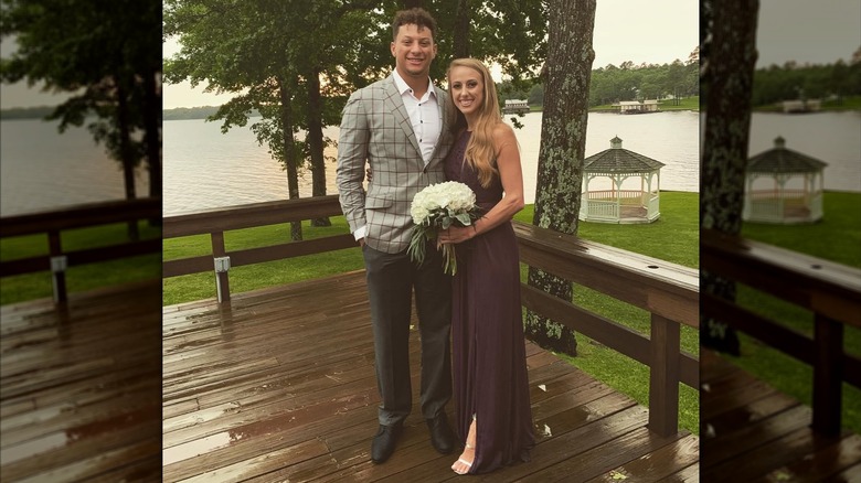 Brittany Mahomes wearing a dark purple dress and posing next to Patrick Mahomes