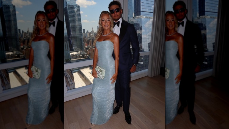 Brittany Mahomes wearing a pale dress and posing in front of Patrick Mahomes