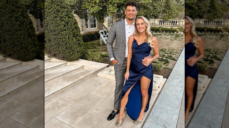 Brittany Mahomes wearing a dark blue dress and posing in front of Patrick Mahomes