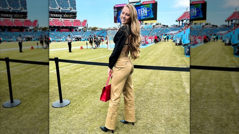 Brittany Mahomes poses in a black top and khaki jeans