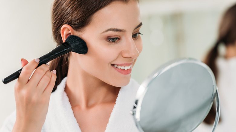 Woman adding bronzer to her face 