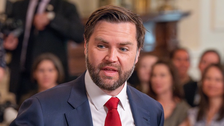 JD Vance attending an event in the East Room of the White House while wearing a suit and red tie.