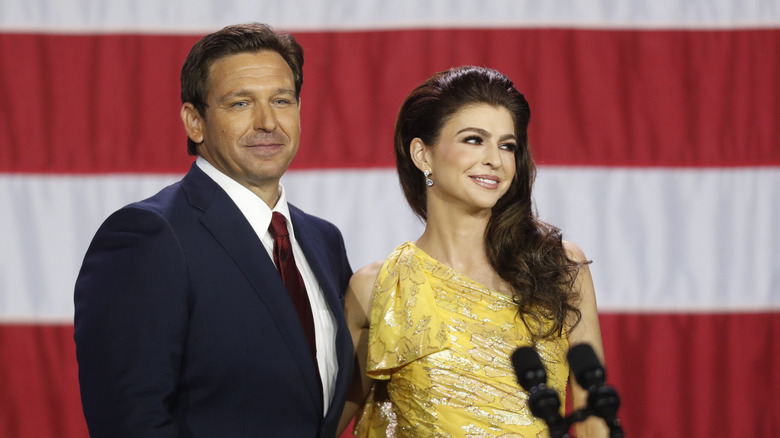 Ron DeSantis standing beside Casey DeSantis in front of an American flag