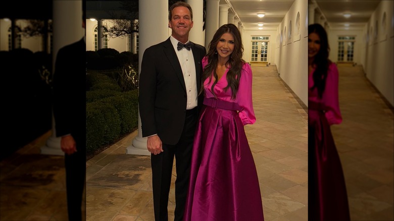 Kristi Noem smiling in a pink dress next to Bryon Noem who's wearing a suit and bowtie.