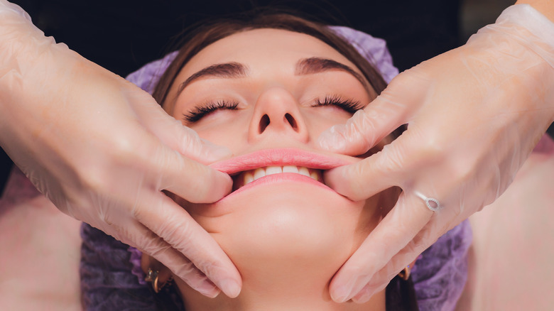 gloved hands massaging woman's mouth