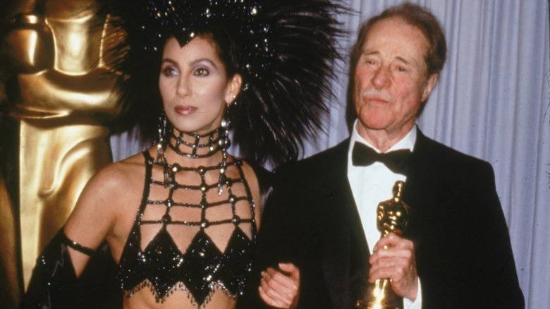 Cher arm in arm with Don Ameche holding his Oscar.