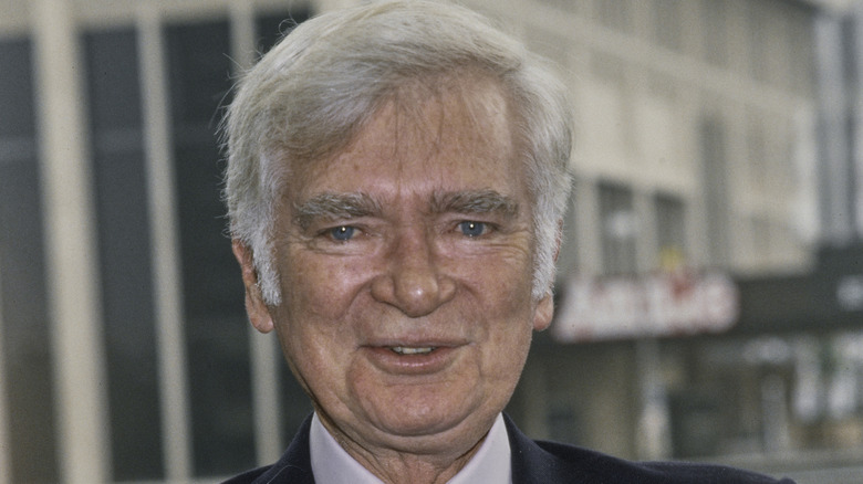 Buddy Ebsen smiling in front of a building.