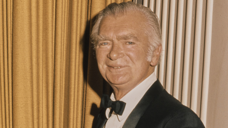Buddy Ebsen smiling in front of a gold curtain.