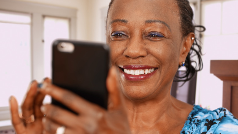 A woman smiling at her phone 
