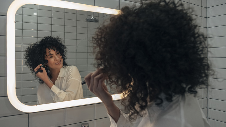 Woman applying makeup in mirror