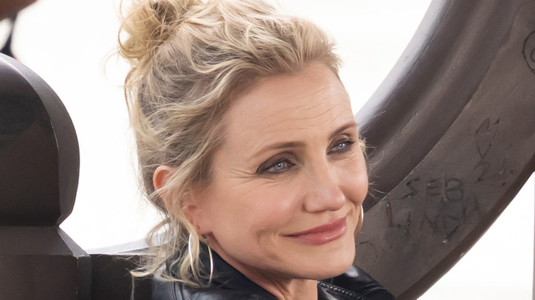 Cameron Diaz smiling and looking to the side with her blonde hair pulled up.