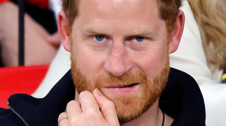 Prince Harry holds a hand to his mouth as he grimaces