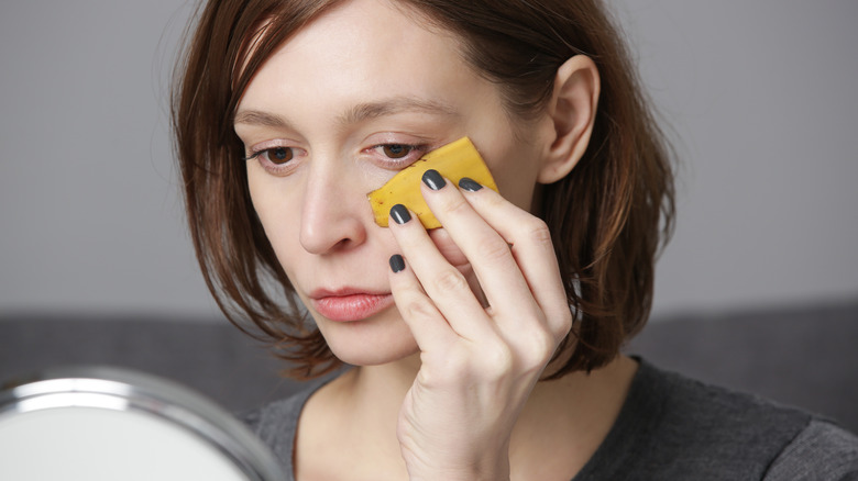 Woman rubbing face with banana peel