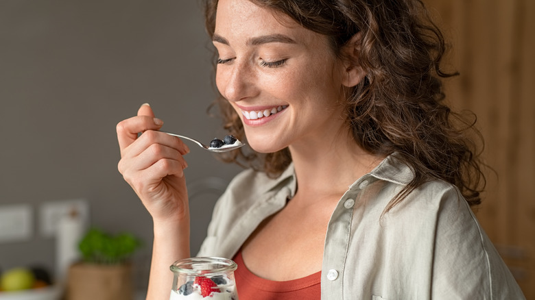 Woman smiling while eating yogurt with berries