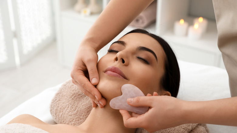 A woman receiving gua sha massage on her face