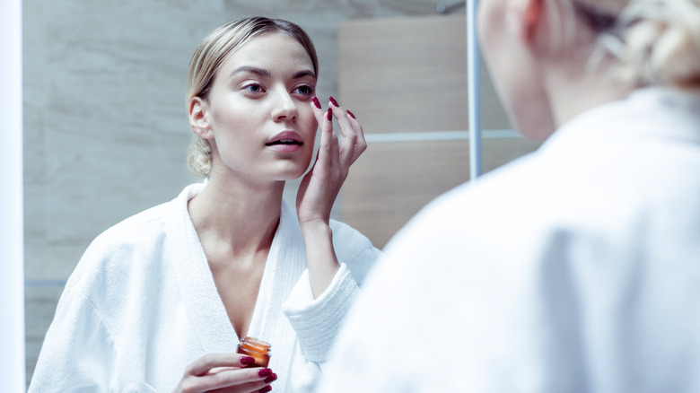 Woman applying eye cream to face