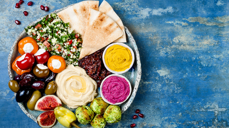 Olives, pita bread, hummus, and other plant-based food items