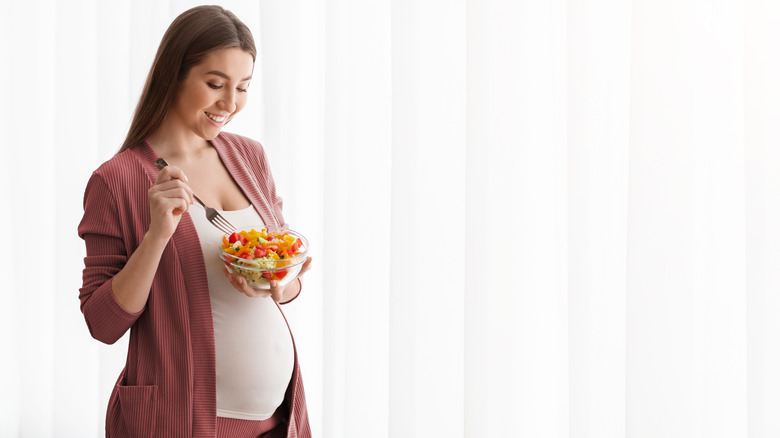 pregnant woman smiling at salad
