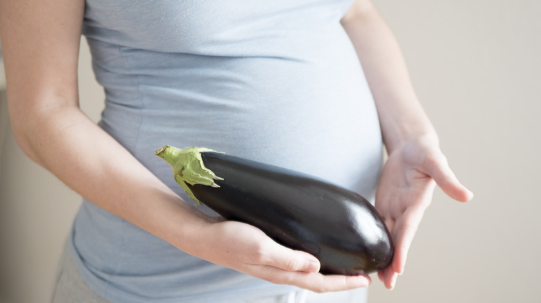 pregnant woman holding an eggplant