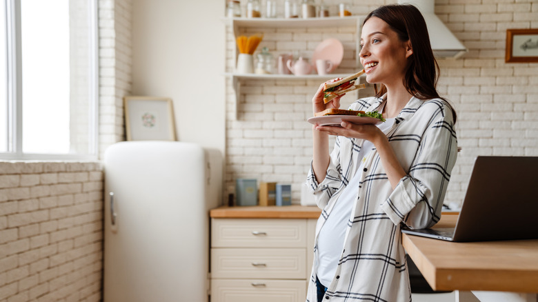 pregnant woman eating a sandwich 