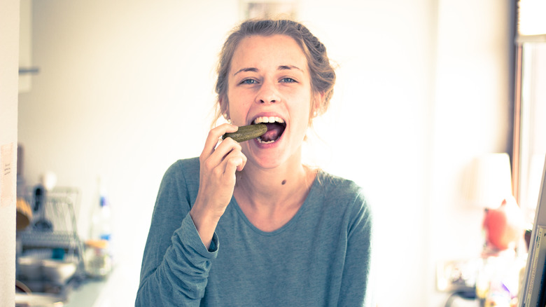 Smiling woman eating pickles