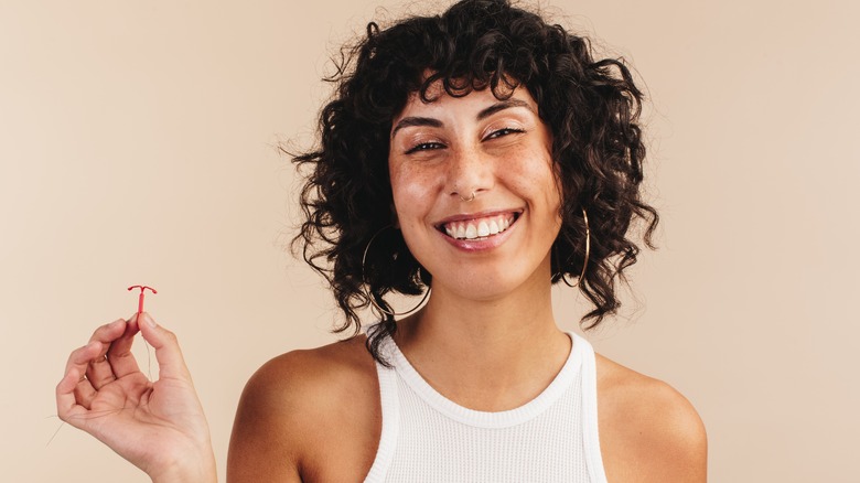 smiling woman holding IUD