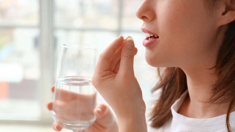 Woman taking pill with water