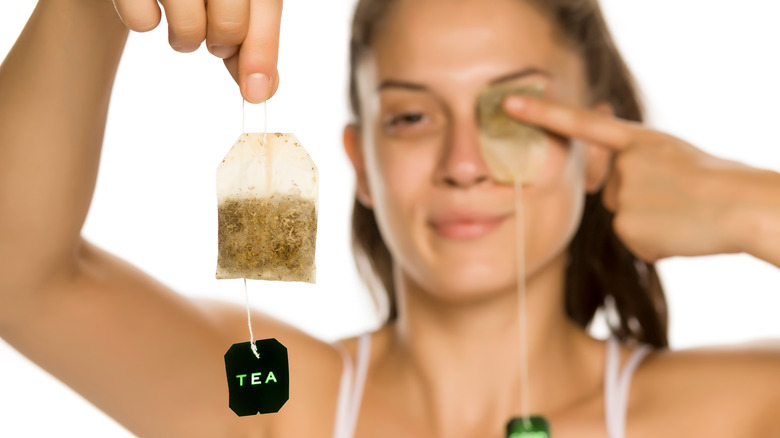 Woman places tea on eye