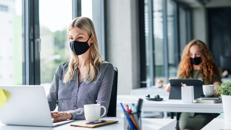 Women wearing masks with laptops