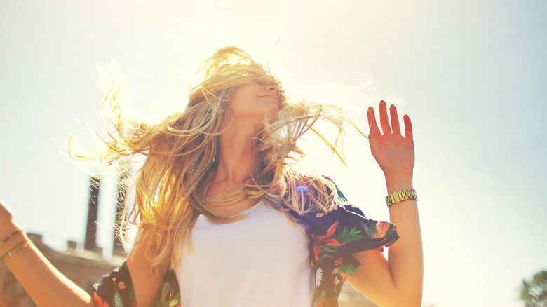 woman smiling with long blonde hair blowing in the wind