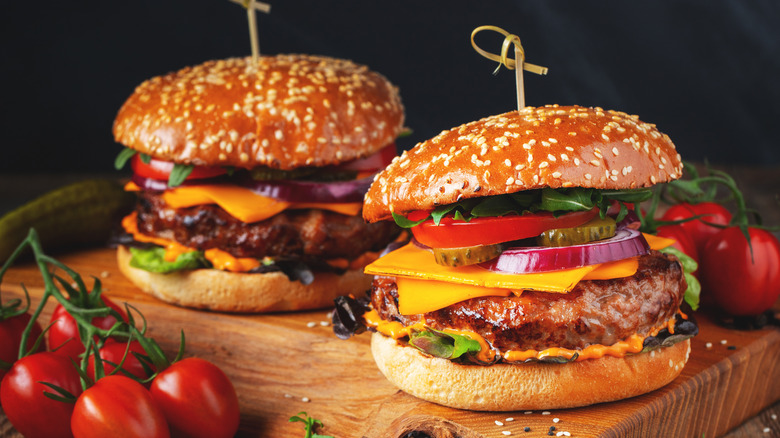 Two burgers on a wooden serving board