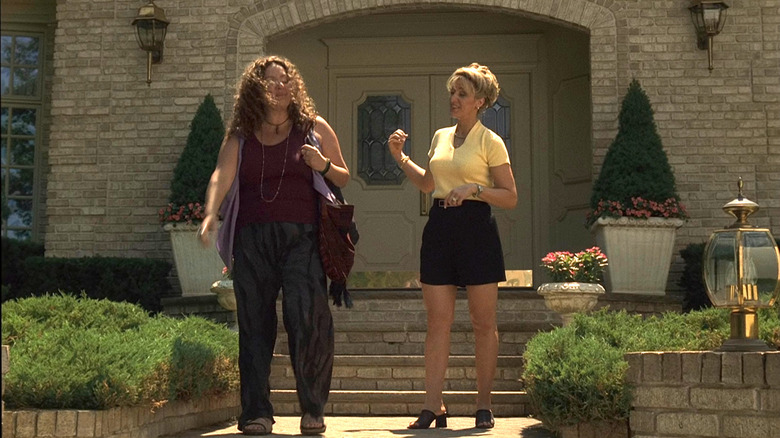 Carmela Soprano standing outside a house in yellow top and skirt