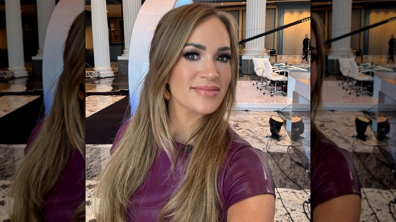 Carrie Underwood smiling with long dark blond hair styled down and straight.