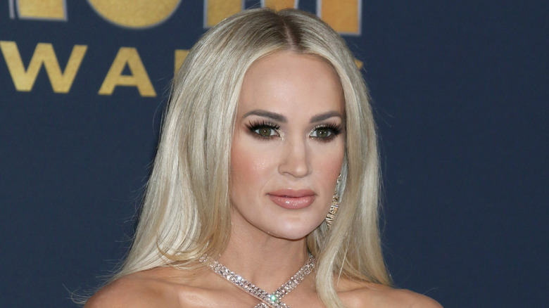 Carrie underwood in front of dark blue backdrop with yellow text