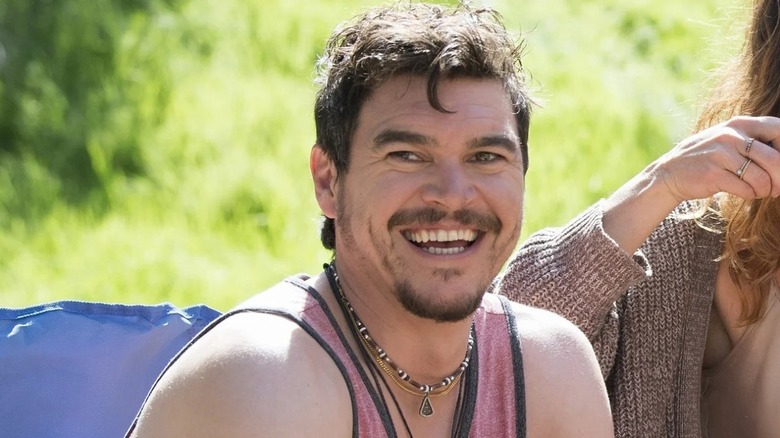 Arturo del Puerto in a pink tank-top grinning in Camping