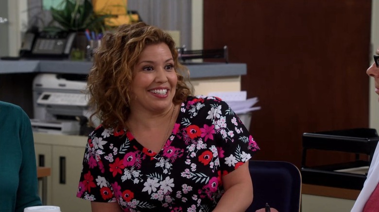 Justina Machado grinning widely in a floral-print top from One Day At A Time
