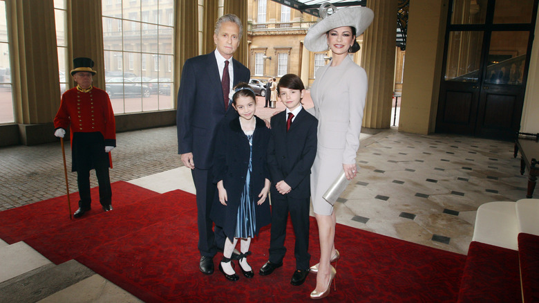 Michael Douglas, Catherine Zeta-Jones, Carys Zeta Douglas, and Dylan Michael Douglas pose inside Buckingham Palace.