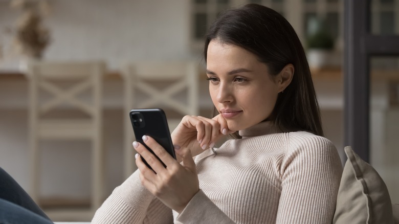 woman holding phone and thinking