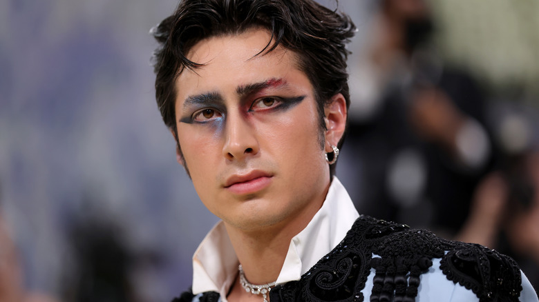 Hudson Williams on the MET Gala red carpet with a half blue half red winged eyeliner look