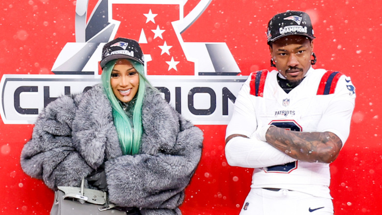 Cardi B and Stefon Diggs standing apart with their arms folded