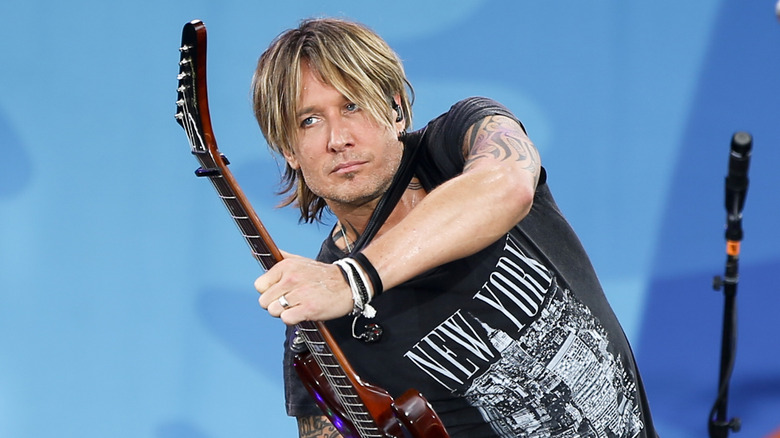 Keith Urban grabbing the neck of his guitar