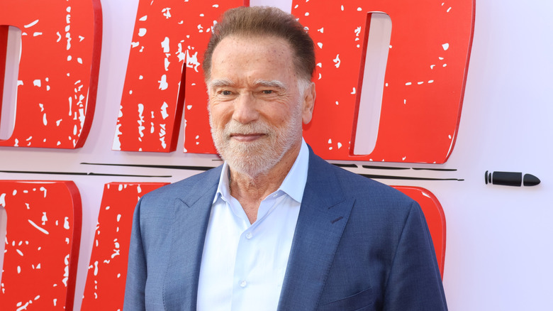 Arnold Schwarzenegger in a blue suit smiling for a photo