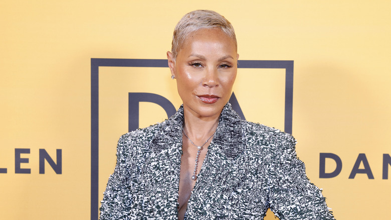 Jada, wearing a textured blazer, standing in front of a yellow background