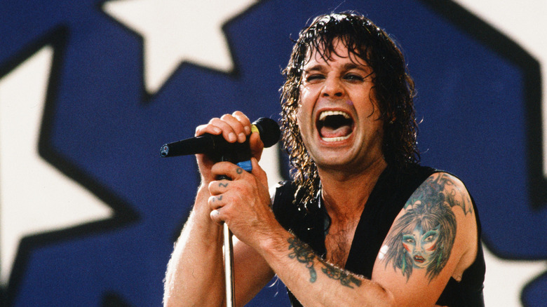 Ozzy Osbourne singing into a microphone on stage